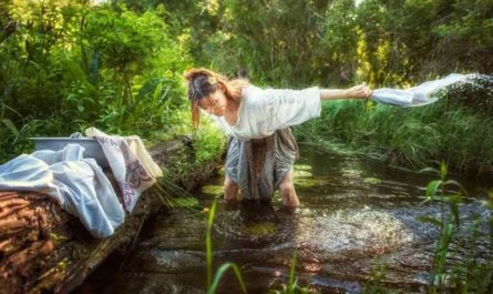 Женщина стирает бельё в водоеме и купается спасаясь от жары
